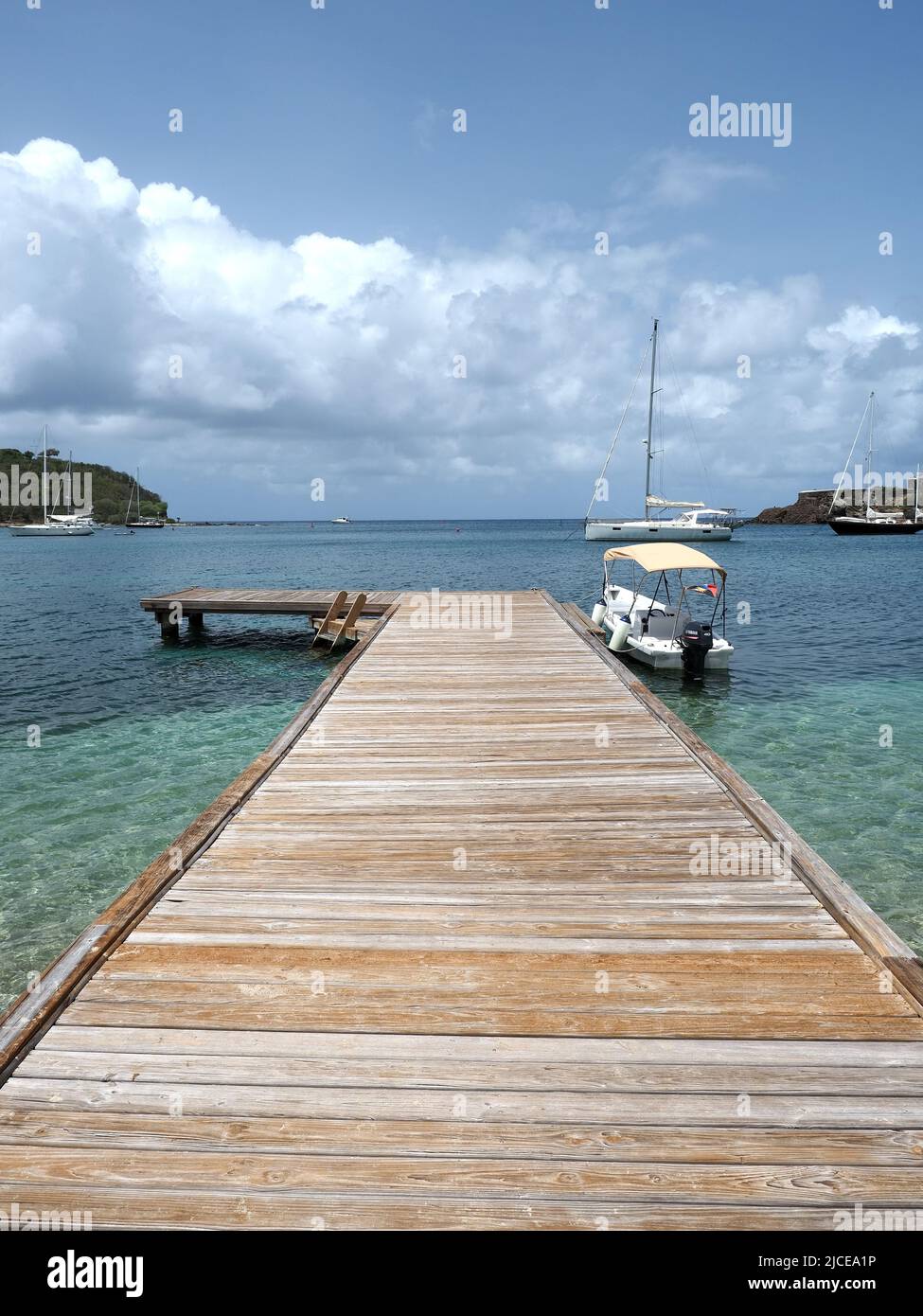 View looking along a wooden jetty stretching out into the Caribbean sea in Antigua Stock Photo