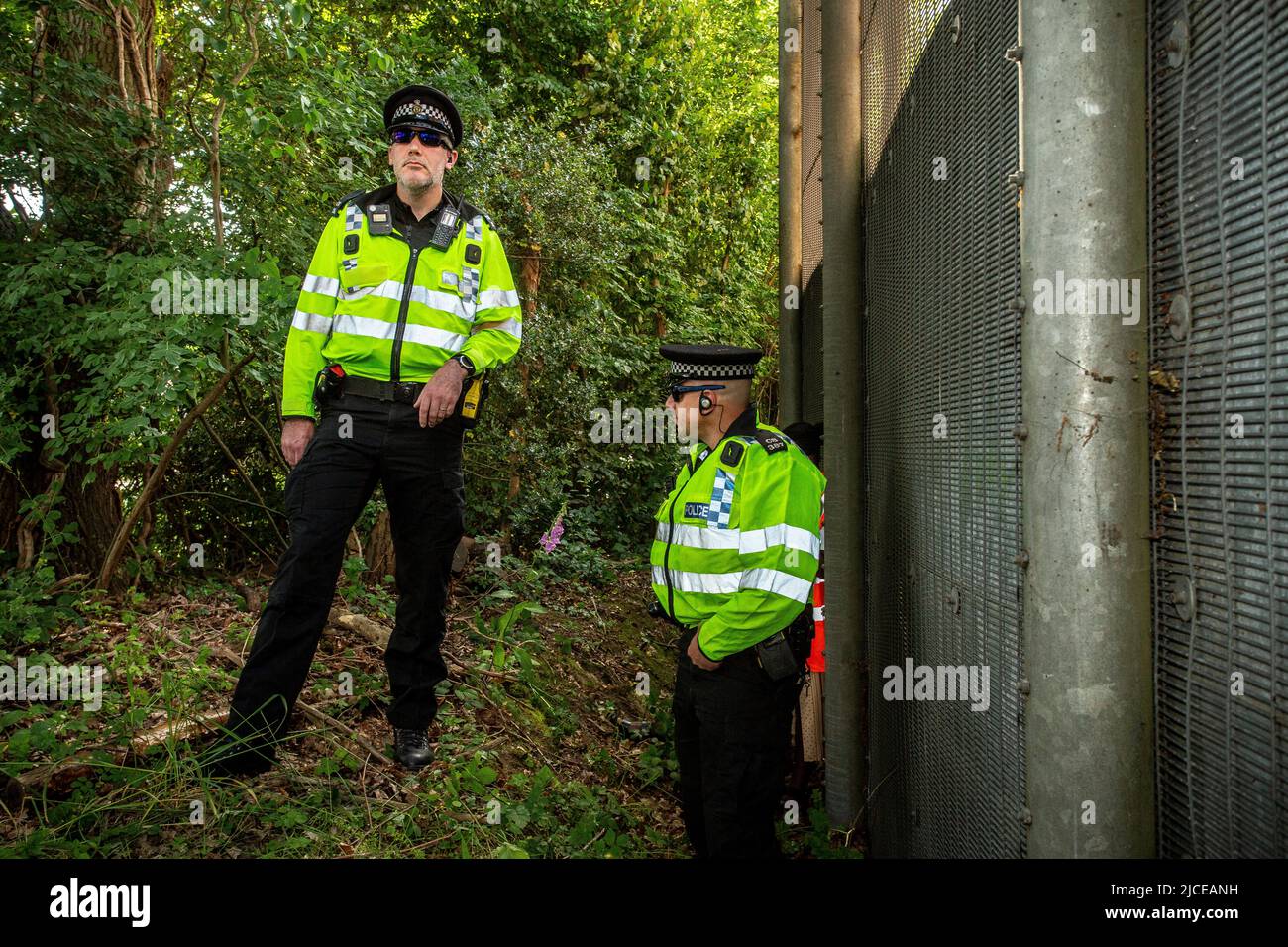 Police stand guard at perimeter fencing against the UK deportation flights to Rwanda outside Brook House Immigration Removal Centre on June 12, 2022 i Stock Photo
