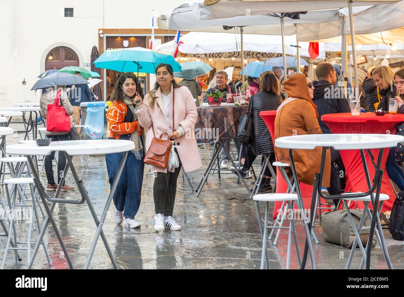 Young women walking  in rain with umbrella, Piazza di Santa Croce, Florence (Firenze), Tuscany Region, Italy Stock Photo