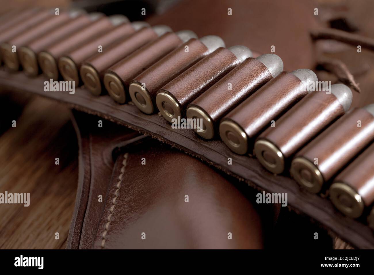 Leather gun belt with ammnunitions and revolver in holster on wooden table Stock Photo