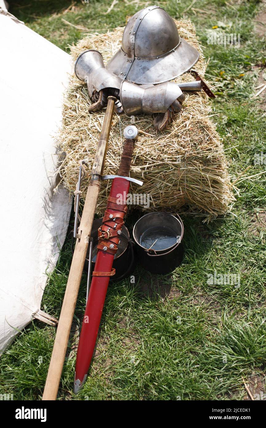 Reconsruction medieval age. Sword, helmet and gauntlet in field camp. Stock Photo
