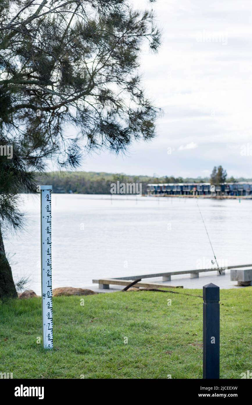 A flood depth marker near Holiday cabins built along the water's edge of Lake Conjola on the NSW, South Coast of Australia Stock Photo
