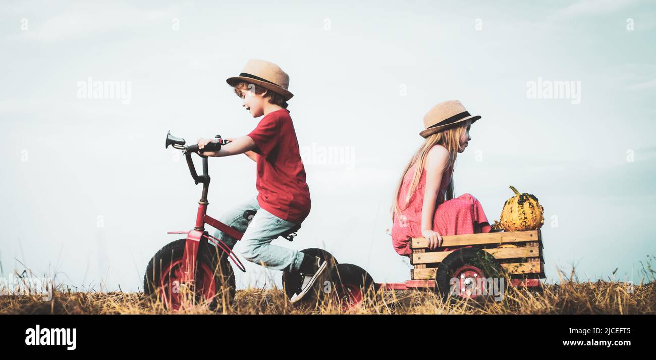 Funny little couple with vintage bike. Two young farmers. Sister and brother on bike in field. Childhood memories. Summer at countryside. Children Stock Photo
