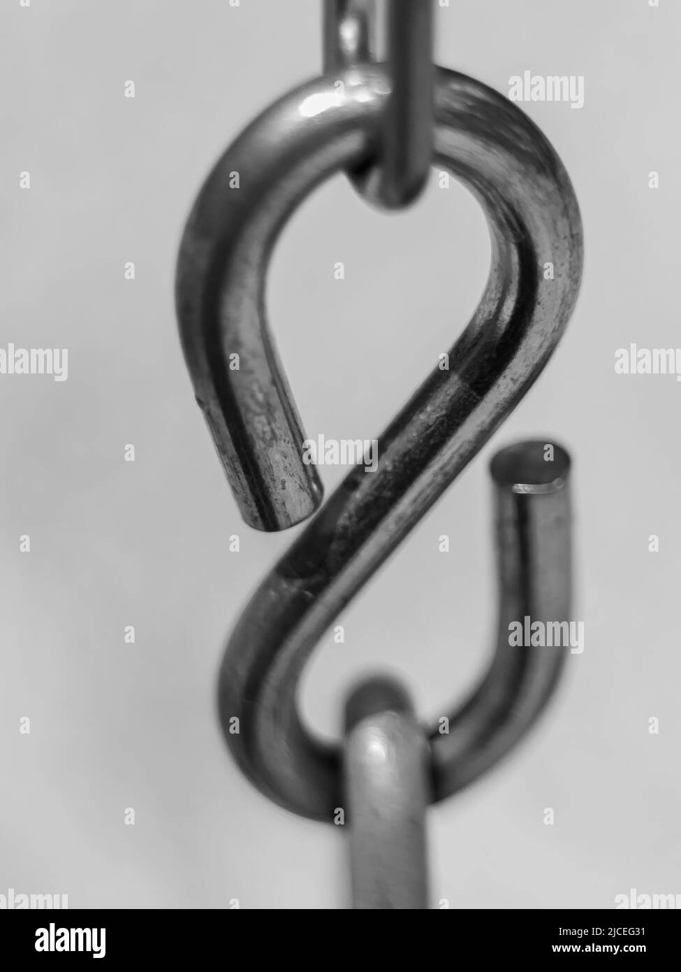 Backward. Stainless steel S shaped Hook. S hook chain. Smooth swivel hook for hanging. Blurred background, selective focus, nobody Stock Photo