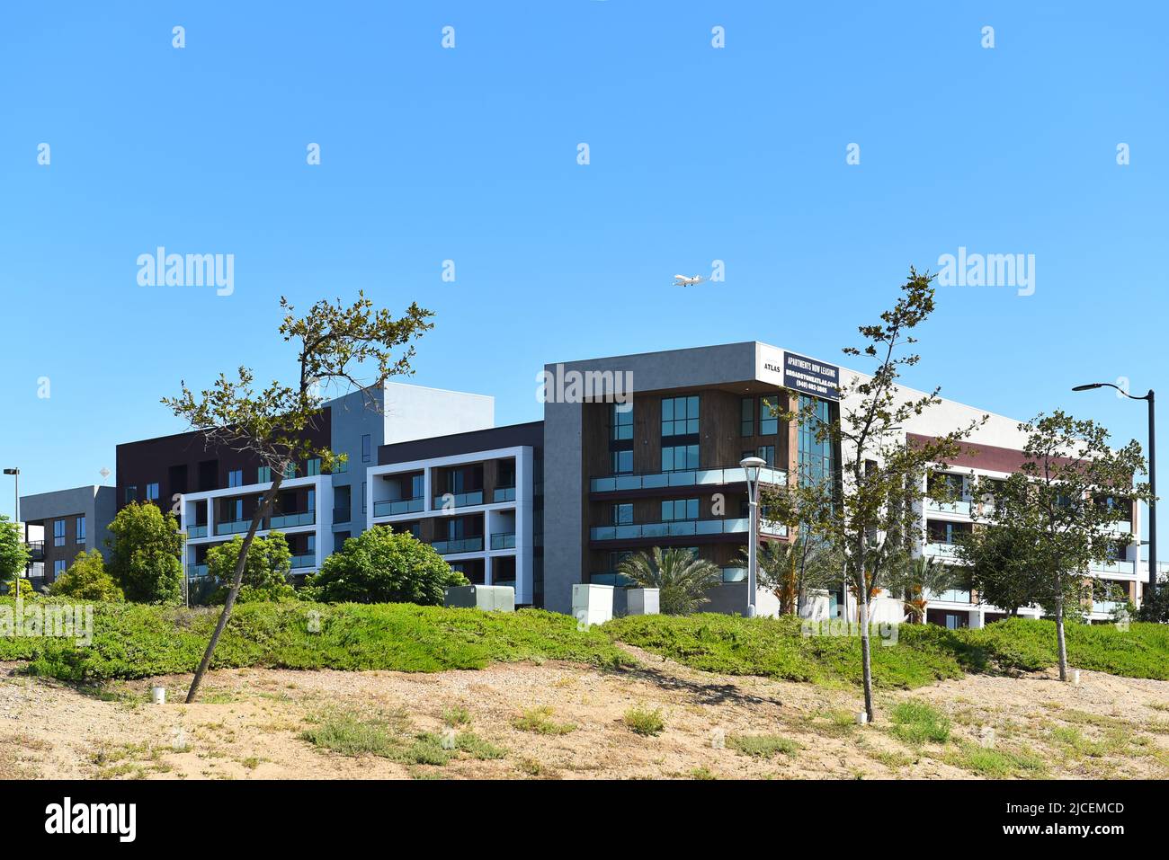 TUSTIN, CALIFORNIA - 12 JUN 2022: Apartments on Redhill Avenue with jet airplane on final approach to John Wayne Airport. Stock Photo