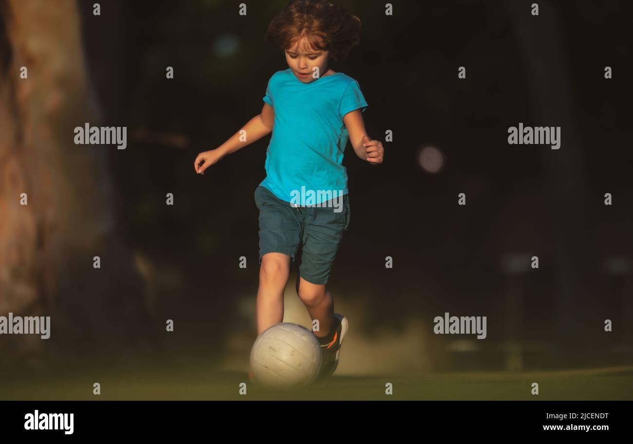 Child playing football on the playground in park. Boy football player kicking football on the
