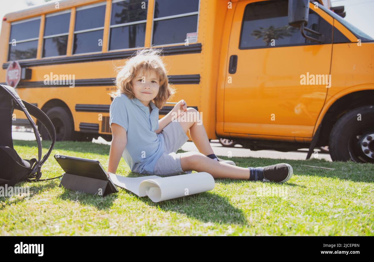 Smart schoolboy doing her homework with digital tablet at school park ...