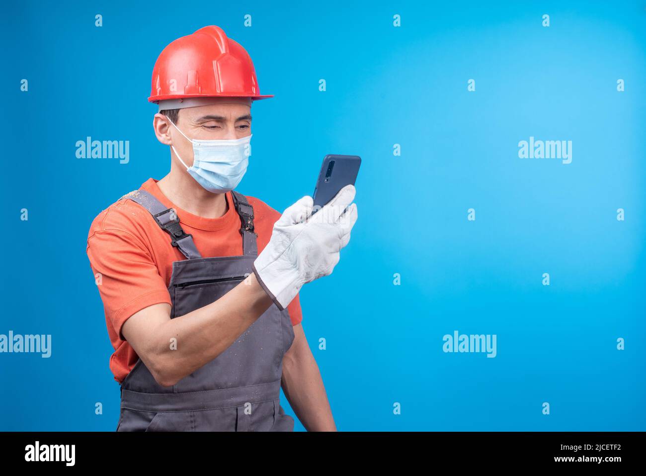 Male builder in face mask using smartphone during work Stock Photo
