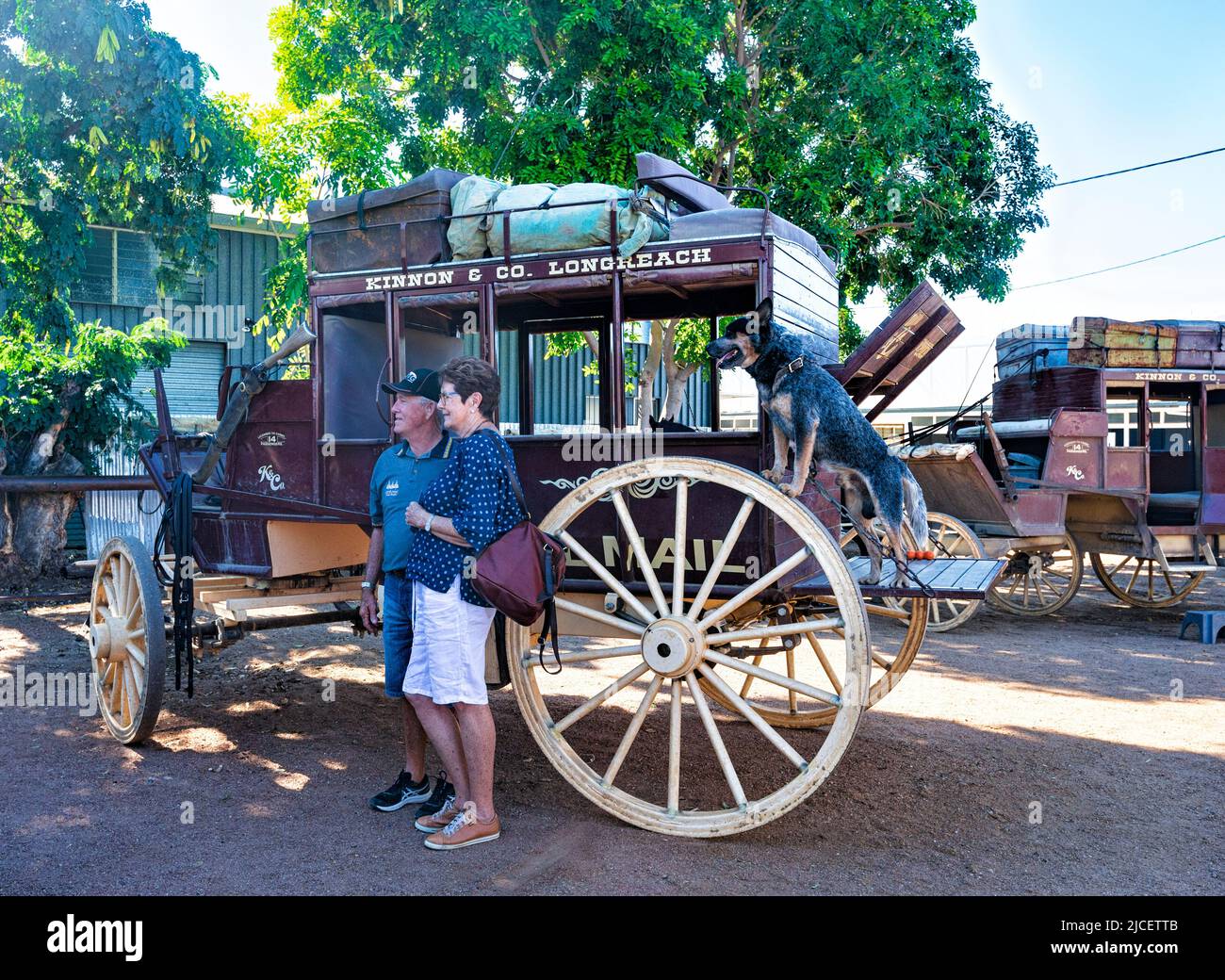 Tourists posing in front of a Cobb & Co coach, a popular tourist attraction by Kinnon and Co, Longreach, Queensland, QLD, Australia Stock Photo