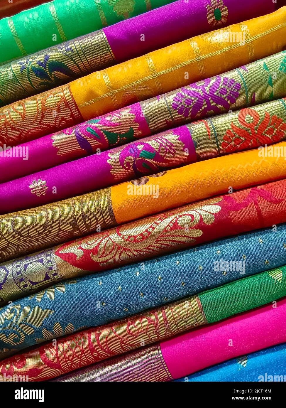 Closeup view of stacked colours saris or sarees in display of Indian retail shop, textile shop. Stock Photo