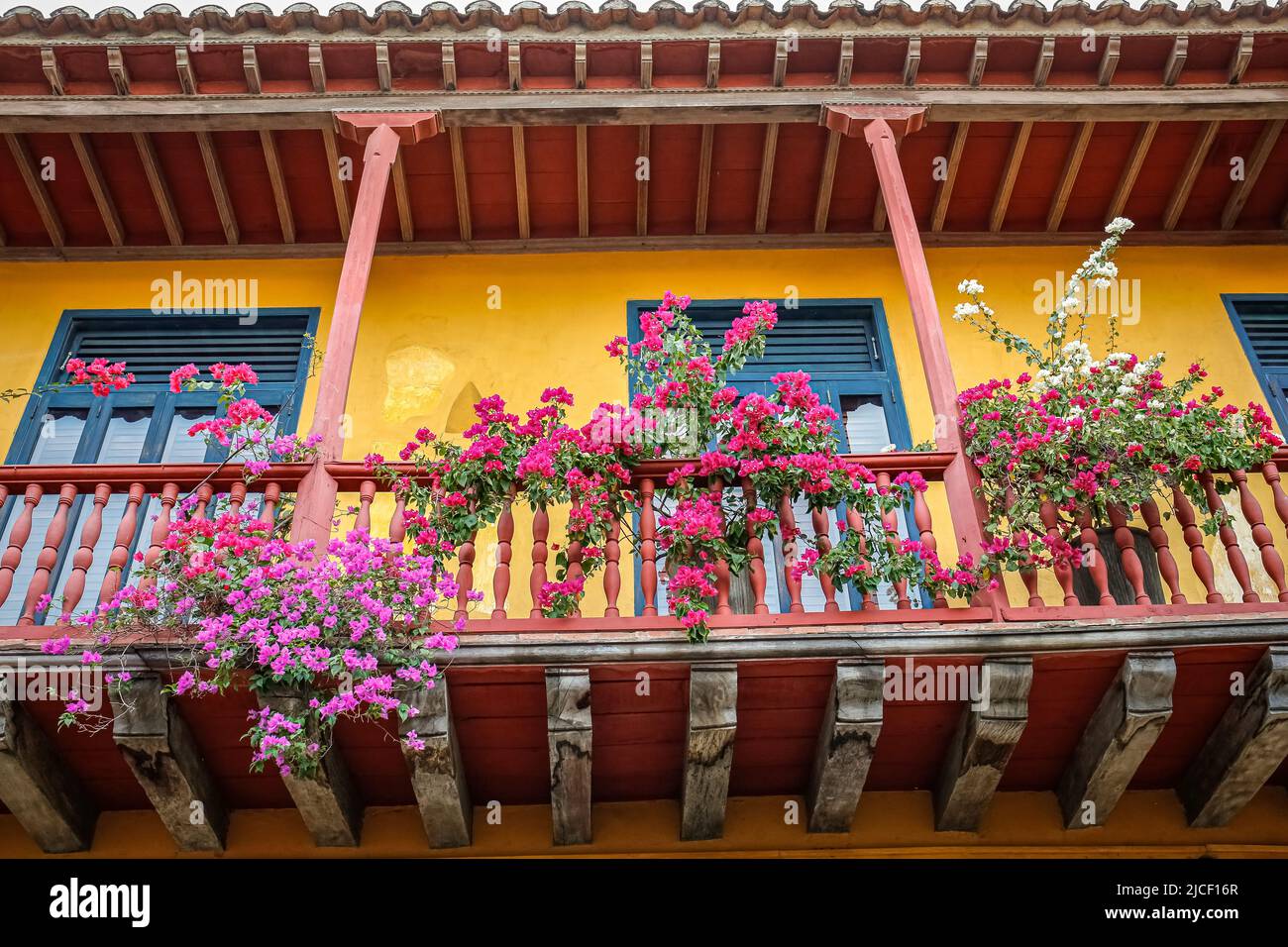 Low angle view of colorful colonial house facade with a flower decorated balcony, Cartagena, Colombia Stock Photo