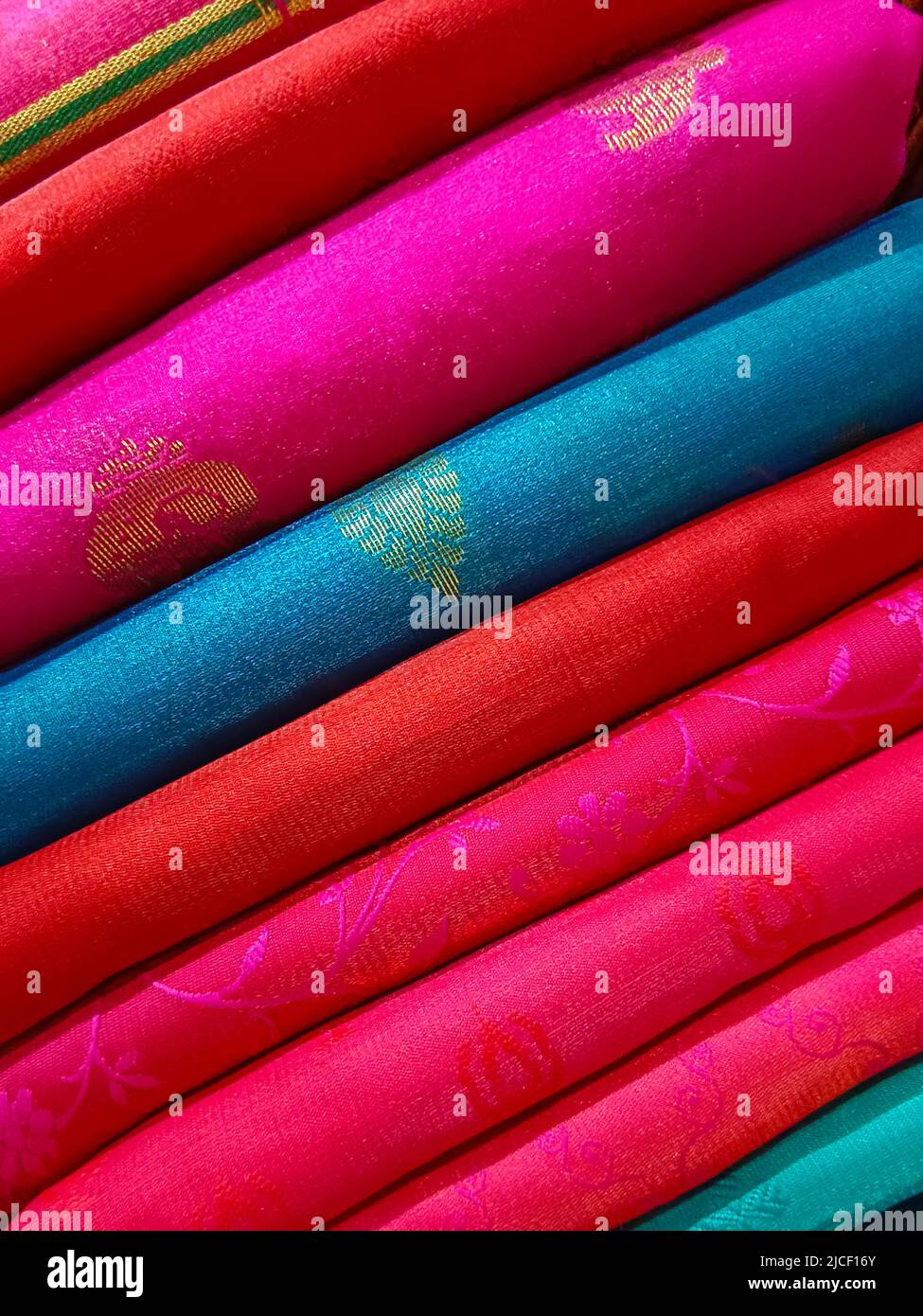 Closeup view of stacked colours saris or sarees in display of Indian retail shop, textile shop. Stock Photo