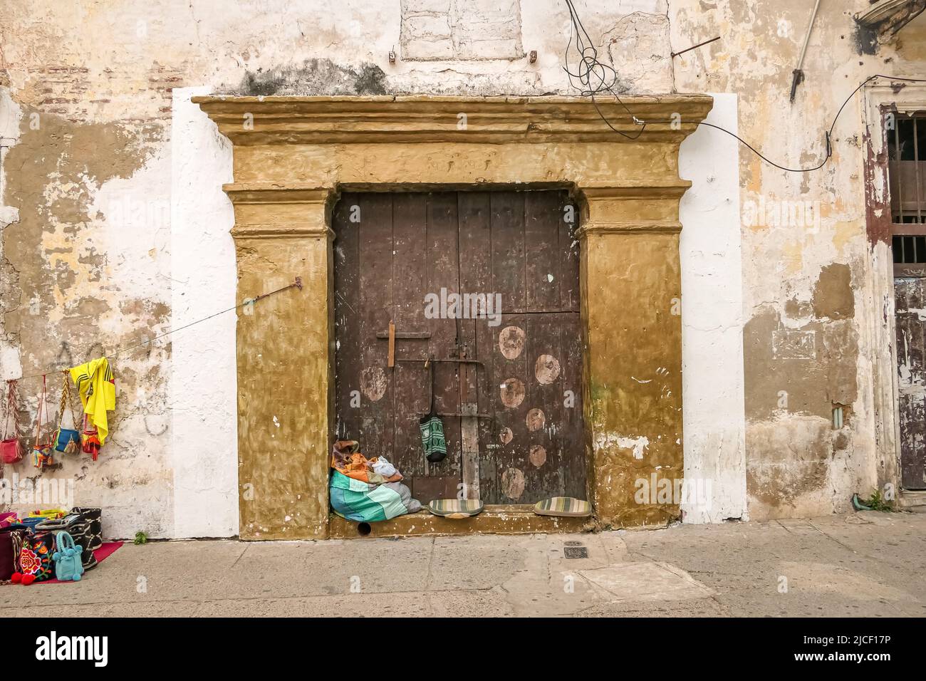 Old church door with colorful selling goods of a street vendor, Cartagena, Colombia Stock Photo