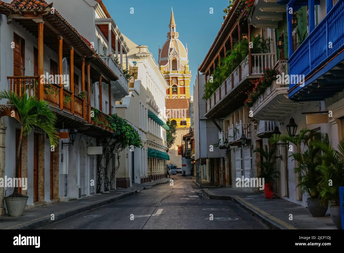 View to the clock tower of Cartagena cathedral with blue sky through a narrow street in shadow, Cartagena, Colombia, Unesco World Heritage Stock Photo