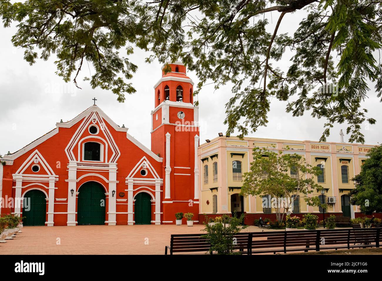View through a tree to a red painted colonial church in Santa Cruz de Mompox, Colombia, World Heritage Stock Photo