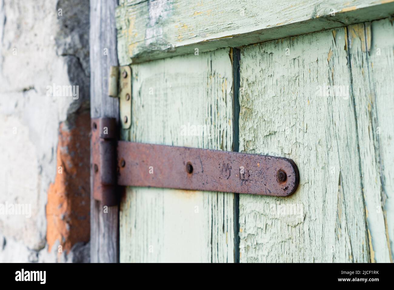 Ancient wooden door background. Fragment of old gate with remnants of green paint and rusty hinges Stock Photo