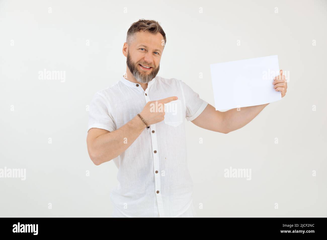 Bearded smiling businessman demonstrating empty blank sheet paper. Mock up, place for text. Promotion career. Copy space Stock Photo