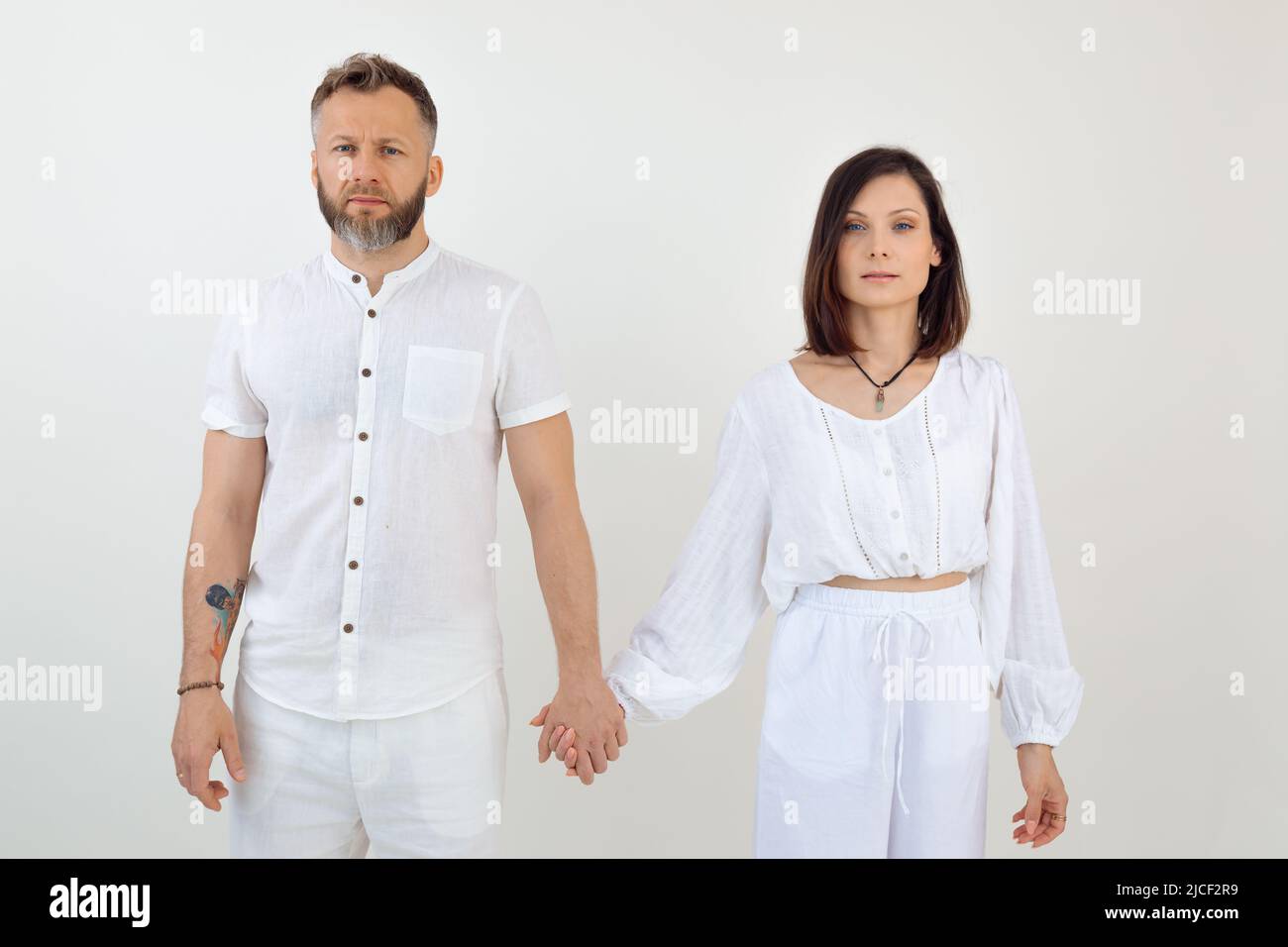 Bearded man and woman, family wearing white fashion clothes, holding hands together. Family business, trust relationship Stock Photo