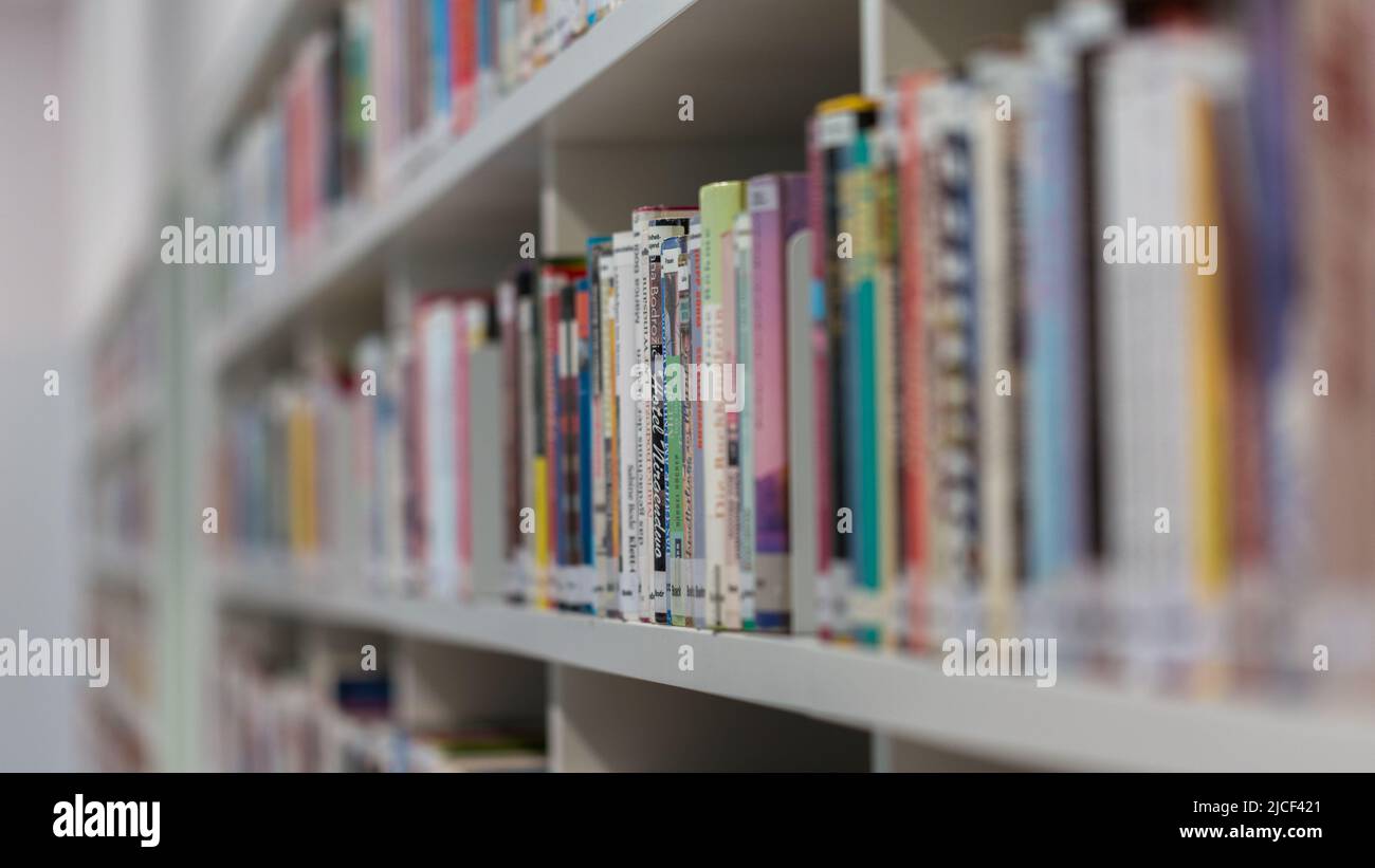 Stuttgart, Germany - Nov 16, 2021: Side view on a bookshelf. Filled with books. Symbol for knowledge, reading and literature. Stock Photo