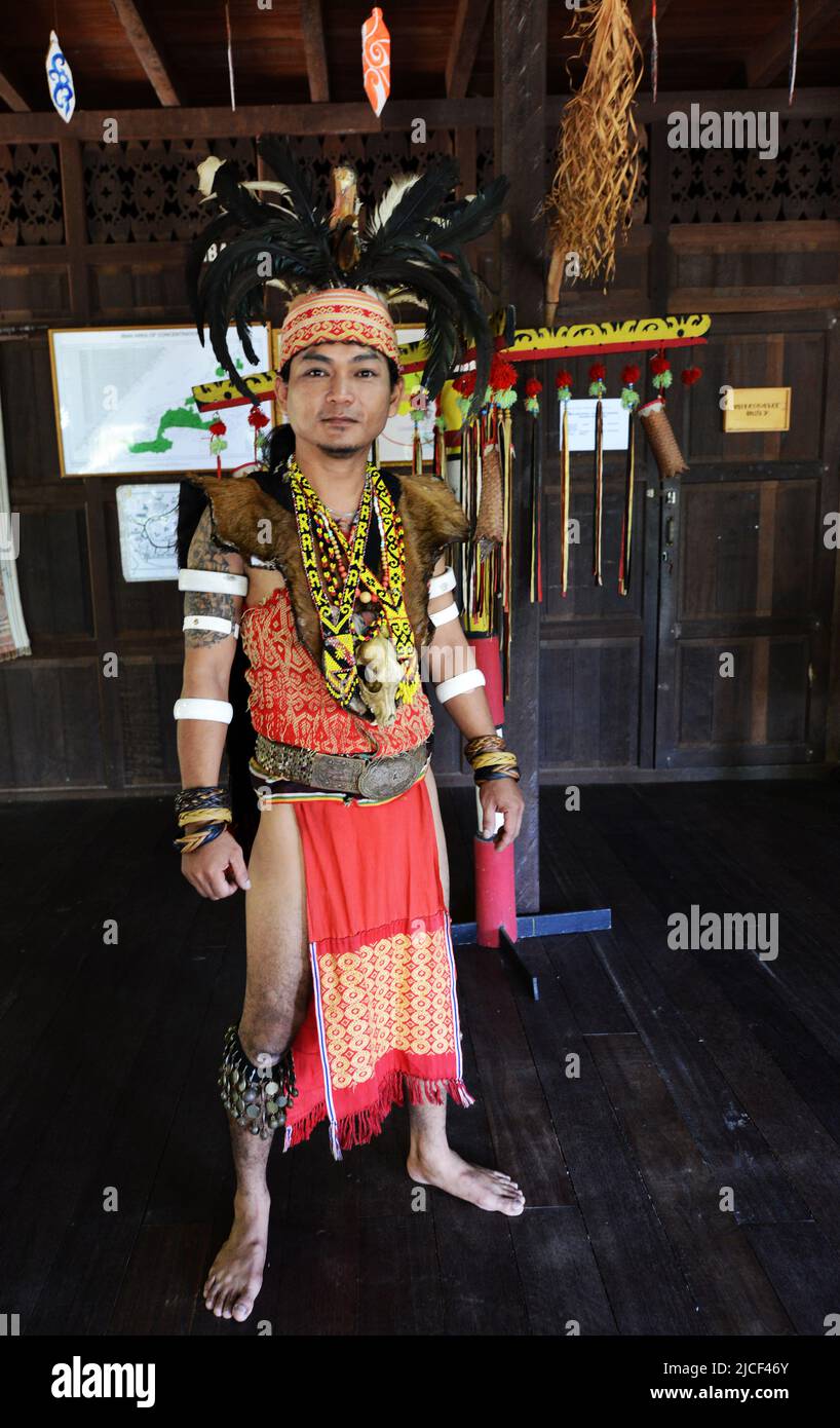 A young Iban man in warrior headhunter regalia, including hornbill feather headdress, at Sarawak Cultural Village near Kuching, Sarawak, Malaysia. Stock Photo