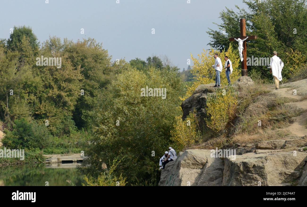 Uman, Ukraine. 21th of September 2017.  Jewish pilgrimags pray by the sacred lake next to to a statue of crucified Jesus Christ.. Stock Photo