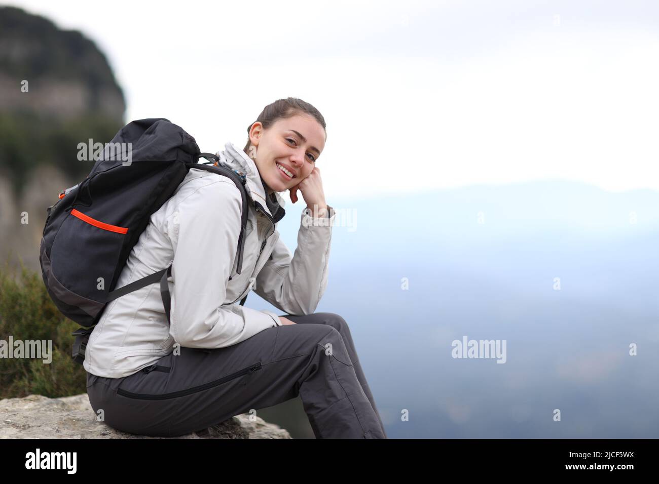 Happy trekker looking at camera sitting in the mountain Stock Photo