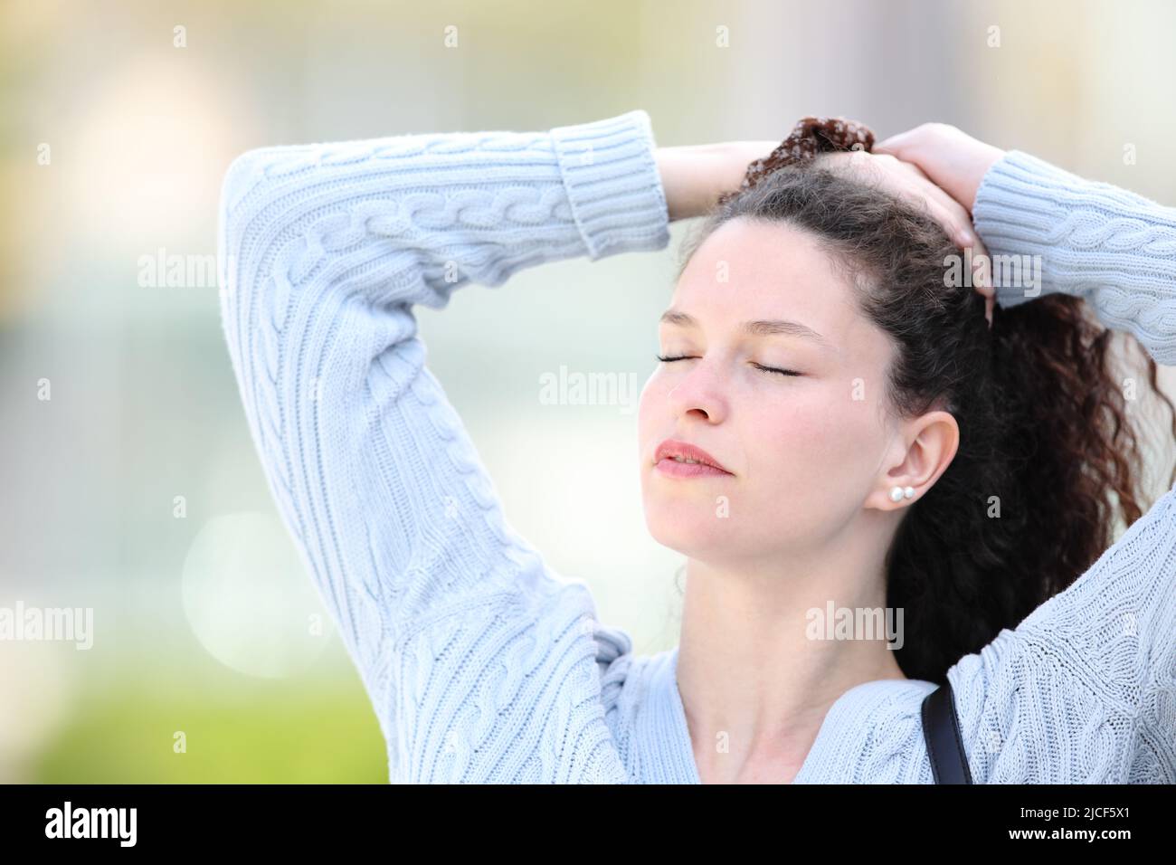 Woman standing in the street doing ponytail Stock Photo