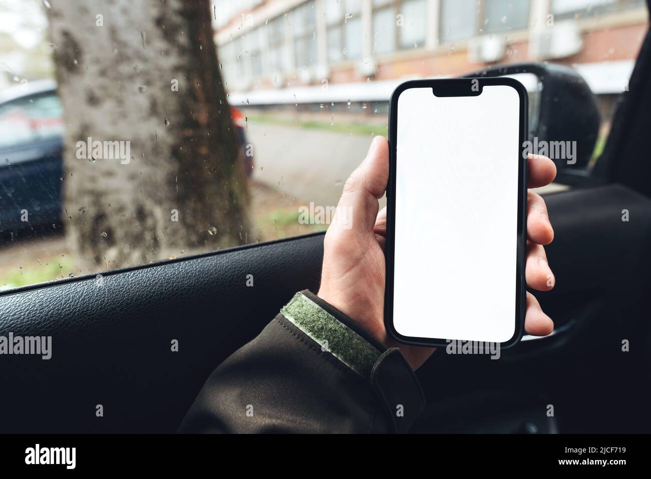 Smartphone mockup, car driver holding mobile phone with blank white screen in vehicle Stock Photo