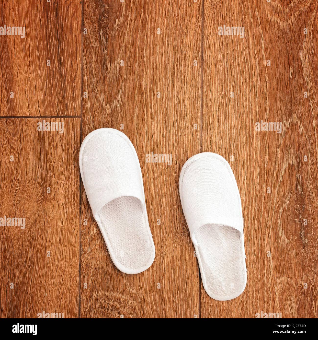 Disposable white slippers on hotel room floor, top view Stock Photo