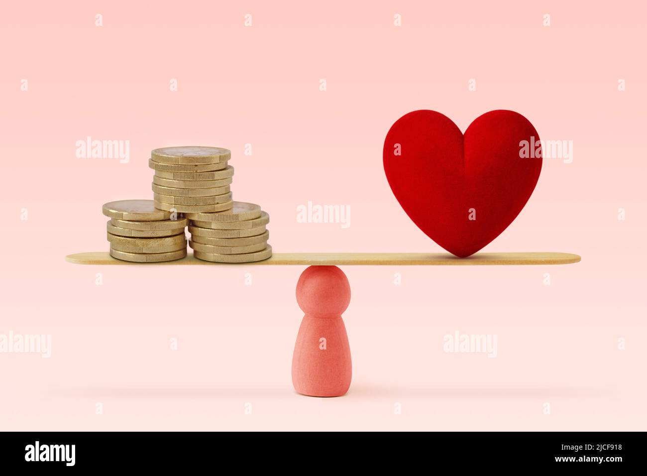Money and heart on scale on pink background - Concept of woman and balance between heart and money Stock Photo