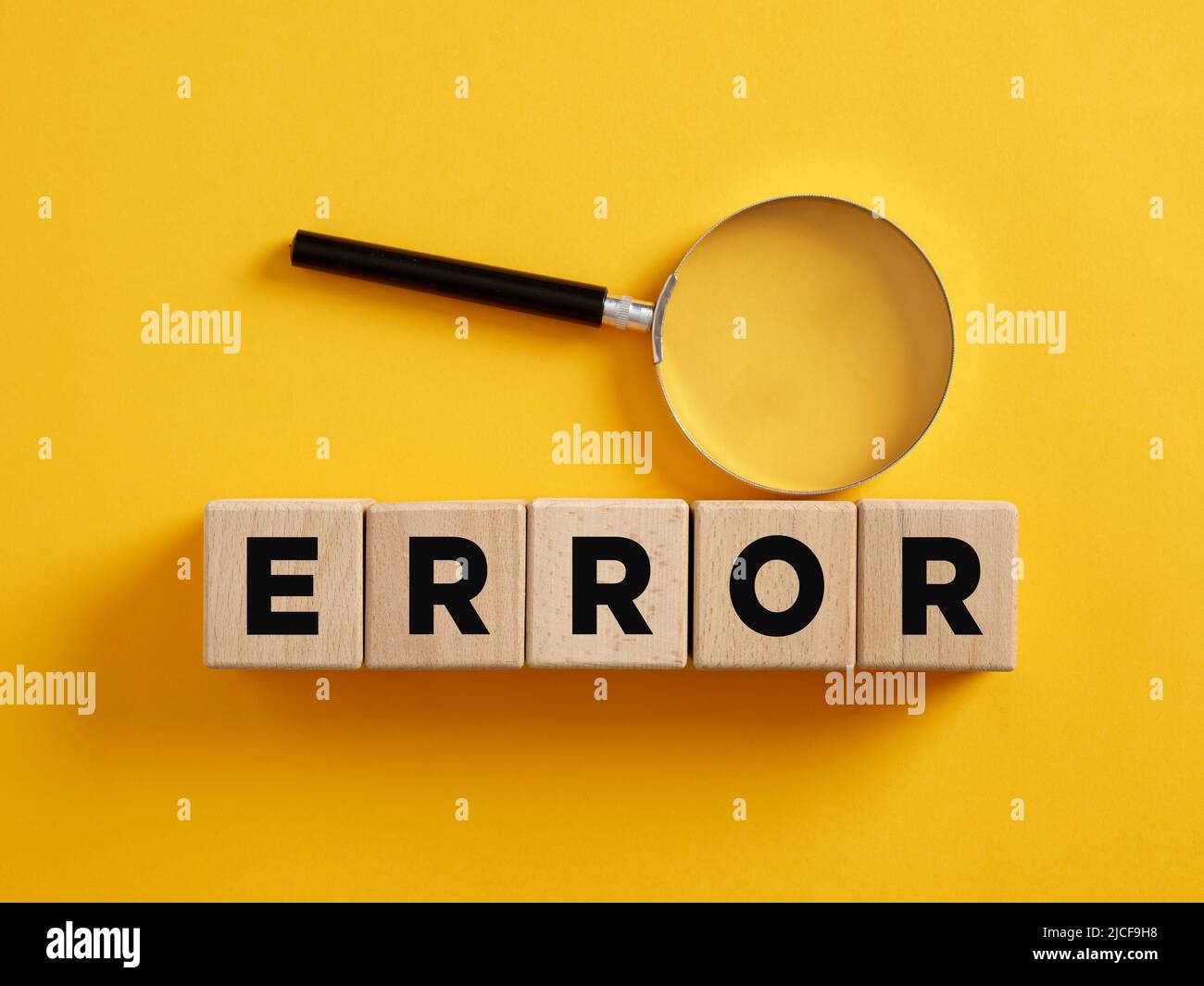 The word error on wooden cubes with a magnifier. To find, reveal or analyze a system error concept. Stock Photo
