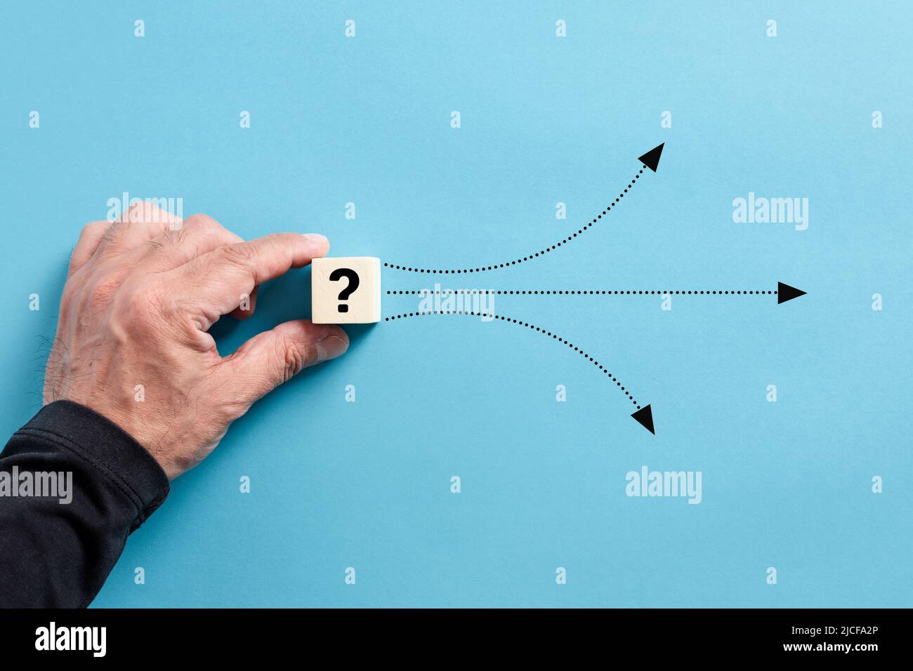 Male hand puts a wooden cube with question mark. Different solution alternatives for an emerging problem or alternative path options. Stock Photo