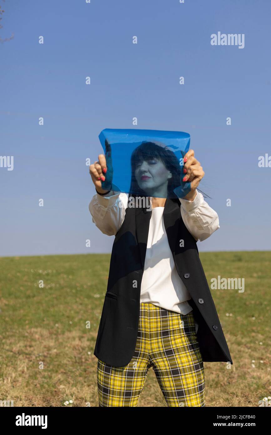Black haired woman with blue color foil on a meadow Stock Photo