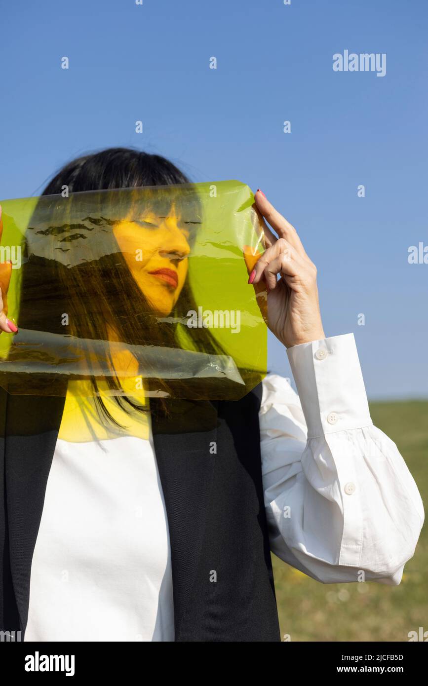 Woman with yellow color foil in front of face Stock Photo