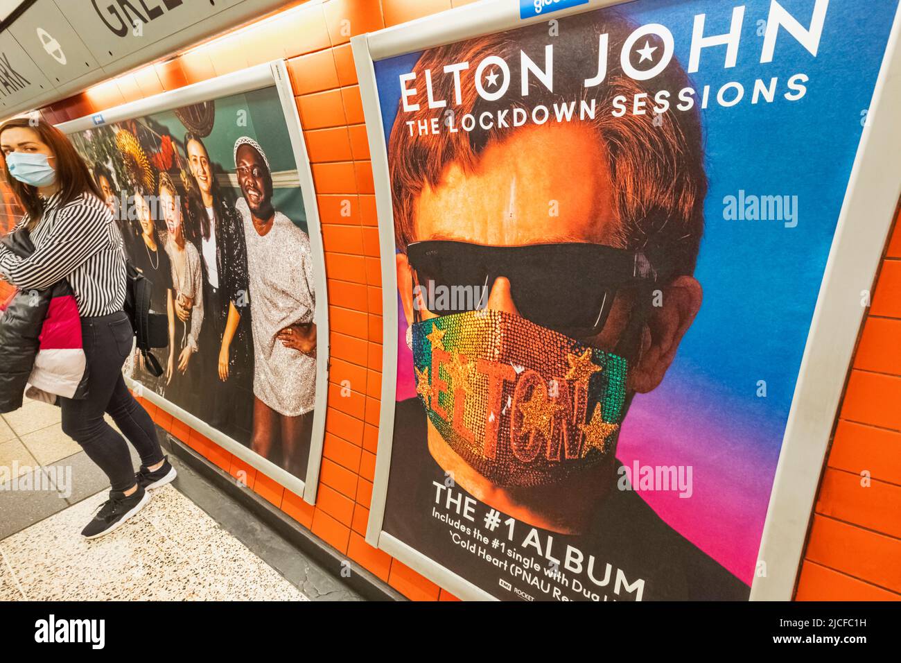 England, London, Subway Station Platform with Elton John Album Advertising Poster and Female Passenger Wearing Surgical Mask Stock Photo