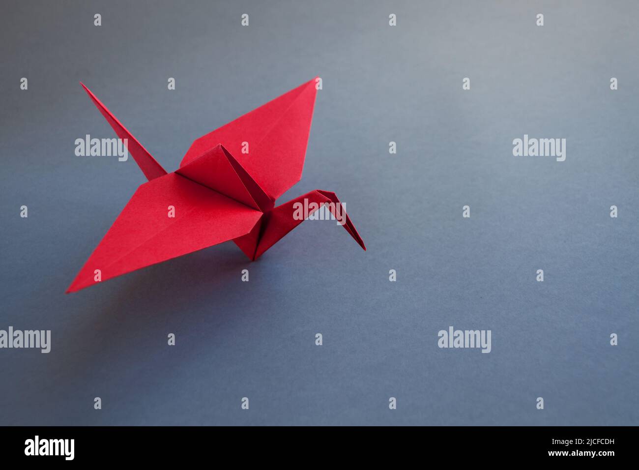 A Red Origami Paper Bird On Paper Background Stock Photo