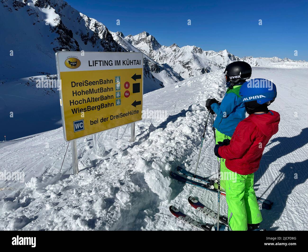 Skiing, two kids in front of signboard in ski resort Kühtai, colorful clothes, winter, nature, mountains, blue sky, Sellraintal, Sellrainer Berge, Kühtai, Tirol, Austria Stock Photo