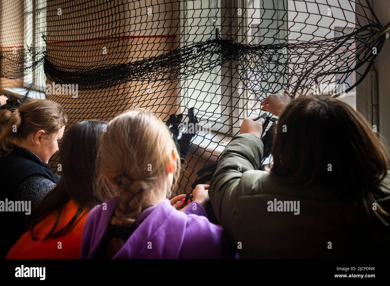 Students and teachers tie camouflage nets in a school in Chernowitz. Classes are canceled. Stock Photo