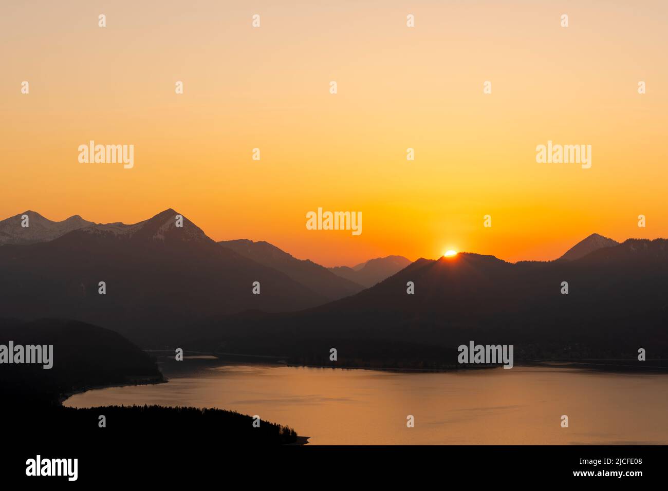 Sunset with orange evening sky over the Walchensee, in the background the Simetsberg, the Estergebirge. Stock Photo