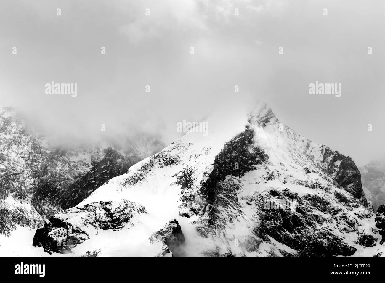 Bad weather with snow and dense clouds with fog at the Alpspitze above Garmisch-Partenkirchen. Seen from Krün. Stock Photo