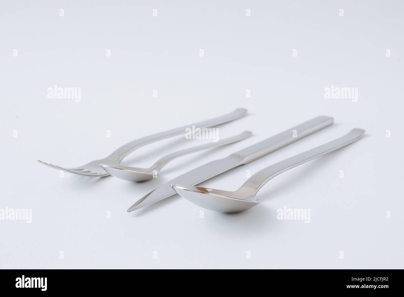Stainless steel cutlery set, knife, spoon, fork, teaspoon on a white background, copy space. Stock Photo