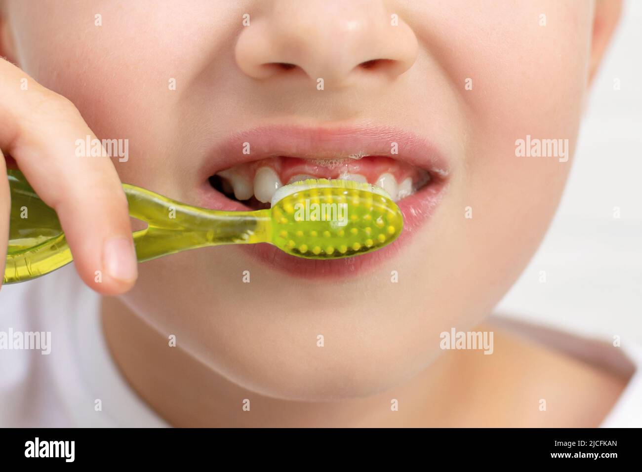 Close-up of an unrecognizable smiling child, he holds toothbrush in his hands and brushes teeth using toothpaste. Morning routine, dental hygiene. Stock Photo