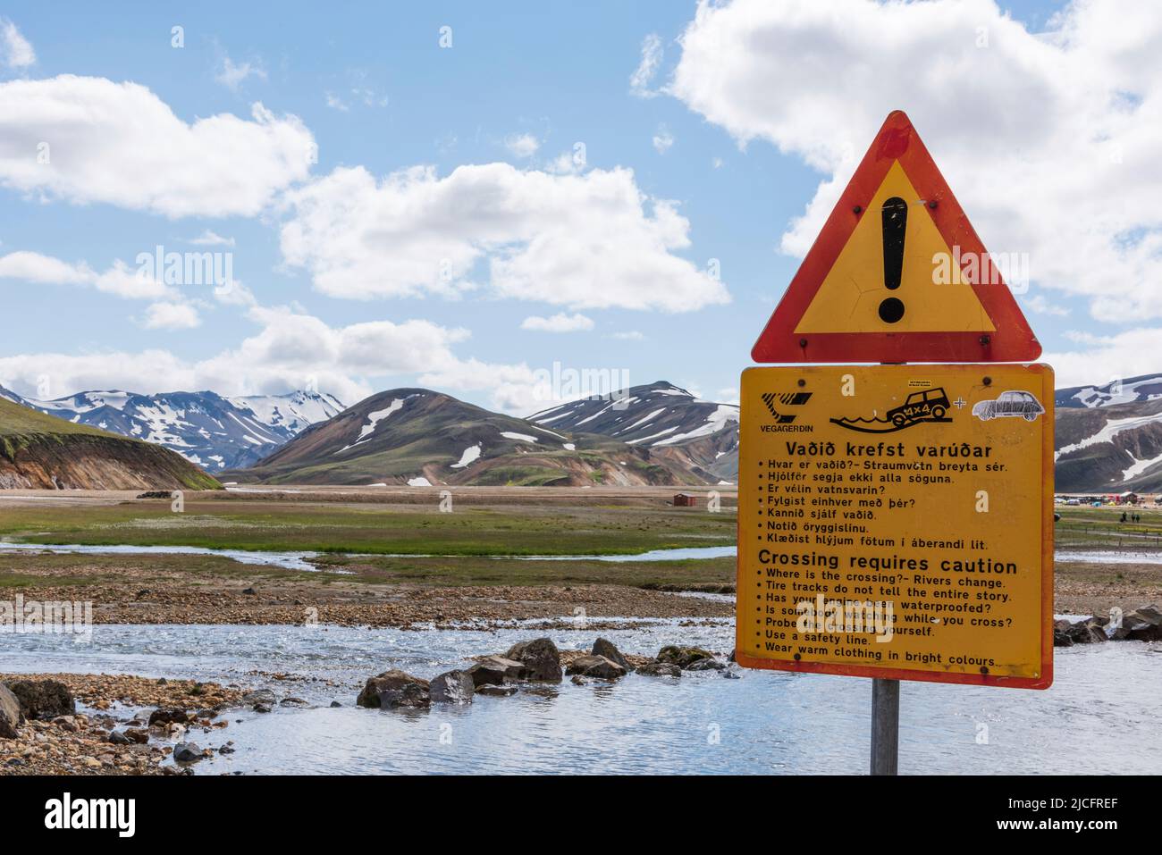 Laugavegur hiking trail is the most famous multi-day trekking tour in Iceland. Landscape shot from the area around Landmannalaugar, starting point of the long-distance hiking trail in the highlands of Iceland. Warning sign 'Crossing requires caution Stock Photo