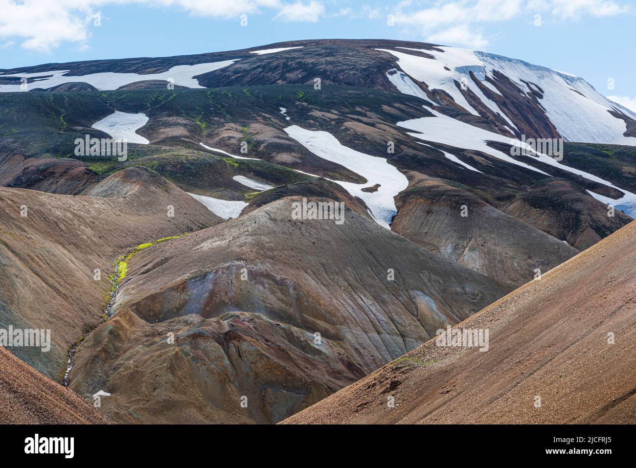 Laugavegur hiking trail is the most famous multi-day trekking tour in Iceland. Landscape shot from the area around Landmannalaugar, starting point of the long-distance hiking trail in the highlands of Iceland. Snow fields. Stock Photo