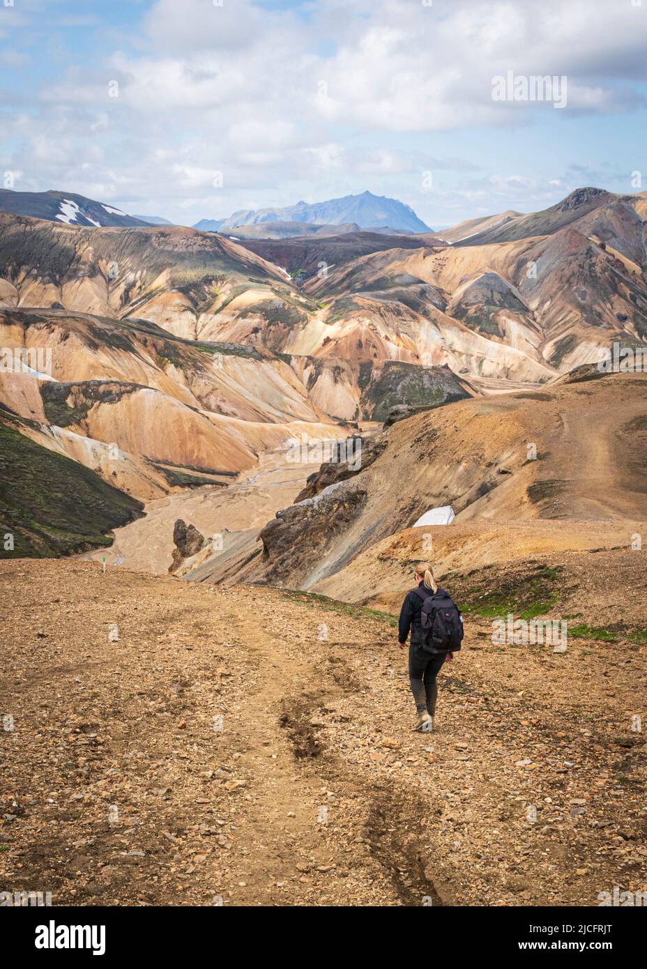 Laugavegur hiking trail is the most famous multi-day trekking tour in Iceland. Landscape shot from the area around Landmannalaugar, starting point of the long-distance hiking trail in the highlands of Iceland. Woman hiking through the beautiful landscape. Stock Photo