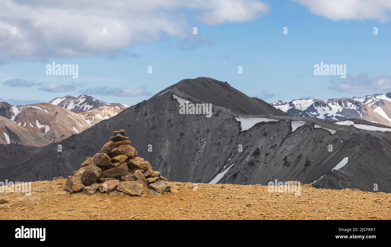 Laugavegur hiking trail is the most famous multi-day trekking tour in Iceland. Landscape shot from the area around Landmannalaugar, starting point of the long-distance hiking trail in the highlands of Iceland. Stone pyramid. Stock Photo