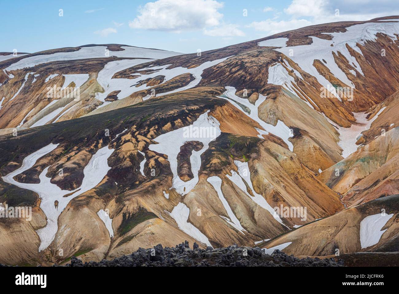 Laugavegur hiking trail is the most famous multi-day trekking tour in Iceland. Landscape shot from the area around Landmannalaugar, starting point of the long-distance hiking trail in the highlands of Iceland. Snow fields. Stock Photo