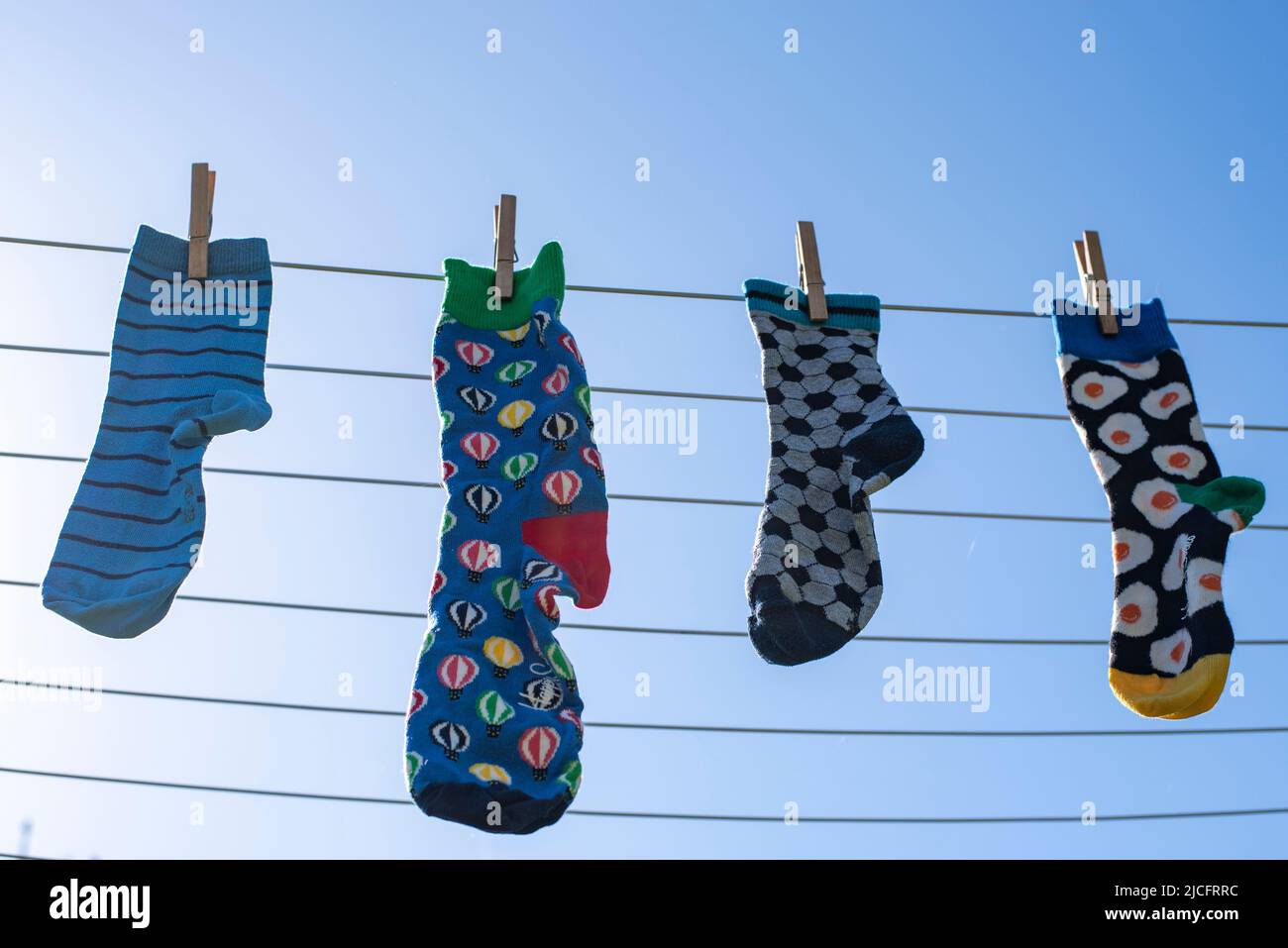 Lonely different socks without partner on a clothesline, symbol image 'Lost Socks Memorial Day'. Stock Photo