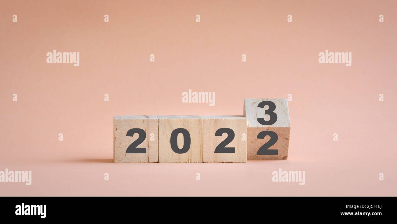 Wooden cube stock flipping, change from 2022 to 2023. Champagne neutral color background, with copy space. Stock Photo
