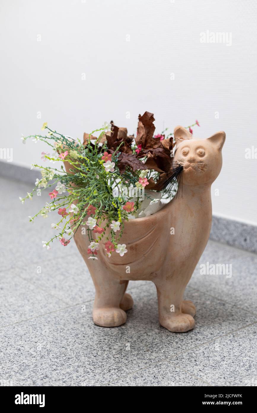 Cat figurine as plant pot with artificial flowers Stock Photo